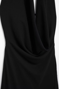 Detail of elegant black pleated halter neck dress showing soft cowl neck draping and texture