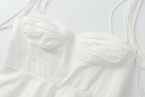 Detail shot of white corset top featuring pleated cups and multi-strap design for women