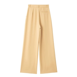 Détail du pantalon plissé à taille haute et jambes larges en abricot crème, tissu lisse