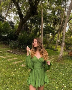Detail of green V-neck mini dress with lantern sleeves in a lush tropical garden setting