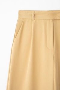 Détail d'un pantalon jaune taille haute avec passants de ceinture et poches latérales