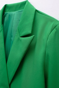 Detailed close-up of peak lapel and textured woven fabric on a green blazer