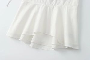 Close-up of asymmetrical layered hemline on white corset top with clean stitching