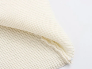 Detailed macro view of white ribbed knit fabric showing fine texture and stitching quality