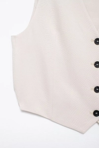 Detail of light beige linen vest showing premium woven texture and four black buttons