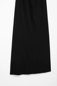 Detail view of the elegant black pleated dress hemline showing premium woven fabric texture