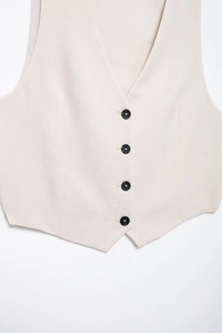 Detail of beige V-neck linen vest showing four black buttons and woven fabric texture