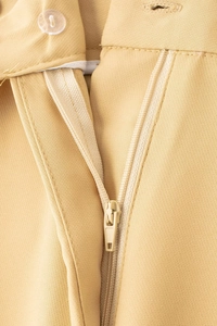 Détail du pantalon décontracté kaki clair avec bouton en résine et fermeture éclair en métal