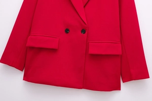 Detail view of red double-breasted blazer showing smooth fabric and black buttons