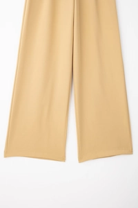 Détail du pantalon large camel montrant le tissu fluide et les coutures de l'ourlet nettes
