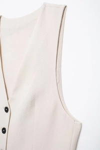Close-up of beige linen vest detailing V-neck, button closure, and fine fabric texture