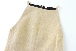 Detail der hellgoldenen Jacquard-Stoffstruktur und Metall-Reißverschluss am Kleid
