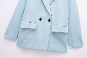 Detailed close-up of light blue double-breasted blazer with buttons and flap pocket