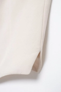 Detail view of the side slit hem on beige linen shorts showing woven fabric texture