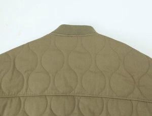 Detail of olive green bomber jacket featuring ribbed collar and onion-quilted pattern