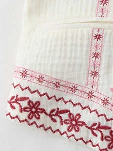 Detailed embroidery on white V-neck vest featuring ethnic patterns and crinkled texture