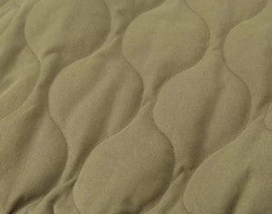 Close-up of olive green quilted bomber jacket with classic wave stitching detail