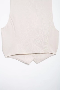 Detailed close-up of beige linen vest hem showing refined tailoring and fabric texture