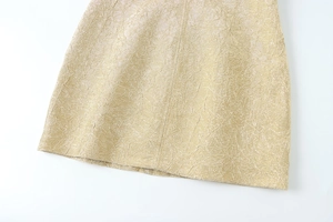 Detail des champagnergoldenen ärmellosen Kleids mit Plissee-Struktur und Metallglanz
