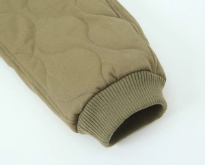 Detail of olive green quilted jacket showing wave stitching and elastic ribbed cuff