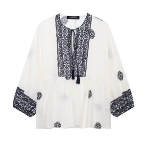 Women's cream boho embroidered top with navy floral patterns and tassel V-neck
