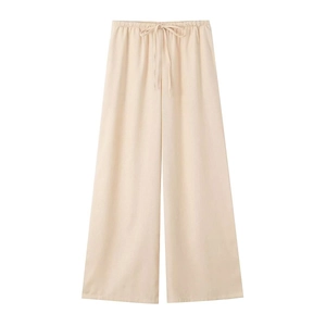 Detail of light beige wide-leg linen trousers with elastic drawstring waistband and texture