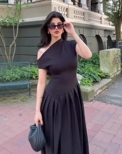 Détail de la robe longue noire à une épaule et plis avec une élégante coupe trapèze
