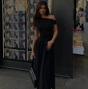Détail d'une élégante robe longue noire à une épaule avec plis à la taille en satin