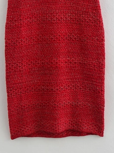 Close-up of red knit dress fabric with metallic gold thread and intricate crochet texture