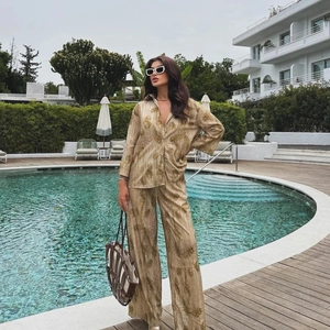 Dettaglio di un elegante completo due pezzi jacquard marrone dorato con pantaloni e camicia