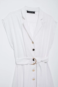 Détail d'une robe chemise blanche sans manches avec boutons dorés et ceinture à anneau