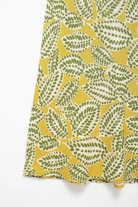 Detailaufnahme von atmungsaktivem gelbem Blumenstoff mit grünen Punktblattmustern