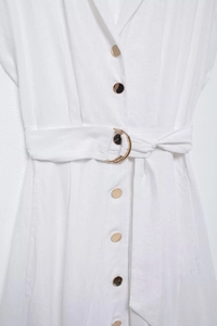 Détail de robe blanche en coton avec boutons dorés et ceinture à boucle métallique en C
