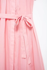 Detail of pink dress featuring a waist tie bow and elegant vertical pleated texture