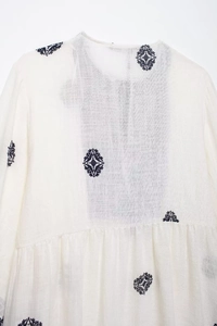 Detailed macro view of diamond embroidery and breathable linen texture on a white summer blouse