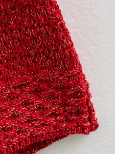 Macro view of bright red knit fabric with golden metallic thread showing detail