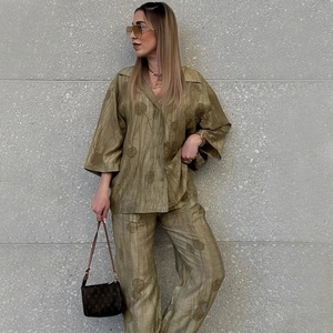 Dettaglio del set camicia jacquard verde oliva e pantaloni a gamba larga con texture sottile