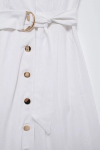 Détail d'une robe chemise en lin blanc avec boutons dorés et ceinture à anneau D