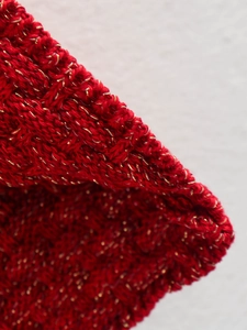 Detailed macro view of red knit fabric with shimmering gold metallic thread texture