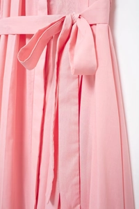 Detail of pink shirt dress featuring a waist tie bow and pleated hem textures
