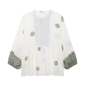Detail of bohemian white blouse with dark green floral prints and textured fabric