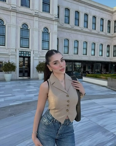 Detail of light khaki slim-fit vest top buttoned up with high-waist denim jeans