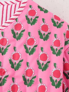 Detail of pink quilted jacket featuring red floral print and striped contrast piping trim