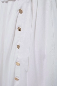 Détail du tissu en coton et lin blanc avec boutons dorés polis et ceinture à la taille