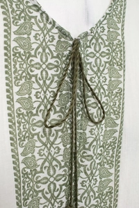 Detail of V-neckline with green paisley print and woven drawstring on white linen top