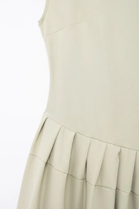 Détail de la robe plissée vert sauge avec taille haute et texture de tissu fine