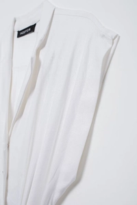 Détail de la texture du tissu de la robe chemise sans manches blanche et étiquette du col