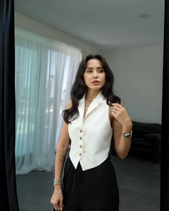 Close-up of white slim fit suit vest with notched lapel and brown buttons for women