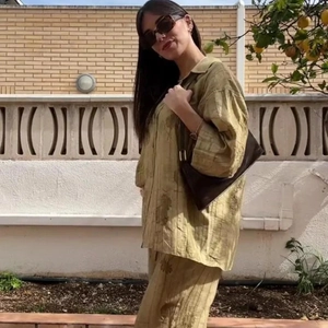 Dettaglio del tessuto testurizzato verde oliva sul set camicia e pantaloni ampi