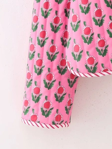 Detailed view of pink floral quilted jacket with vertical stitching and striped trim